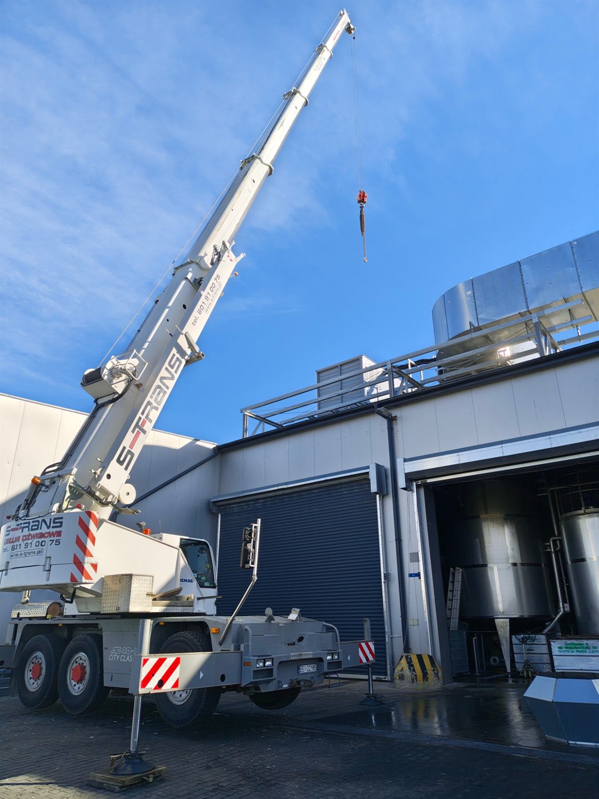 Dźwig Demag AC 40-1 City firmy S-Trans przy montażu urządzeń na dachu hali produkcyjnej